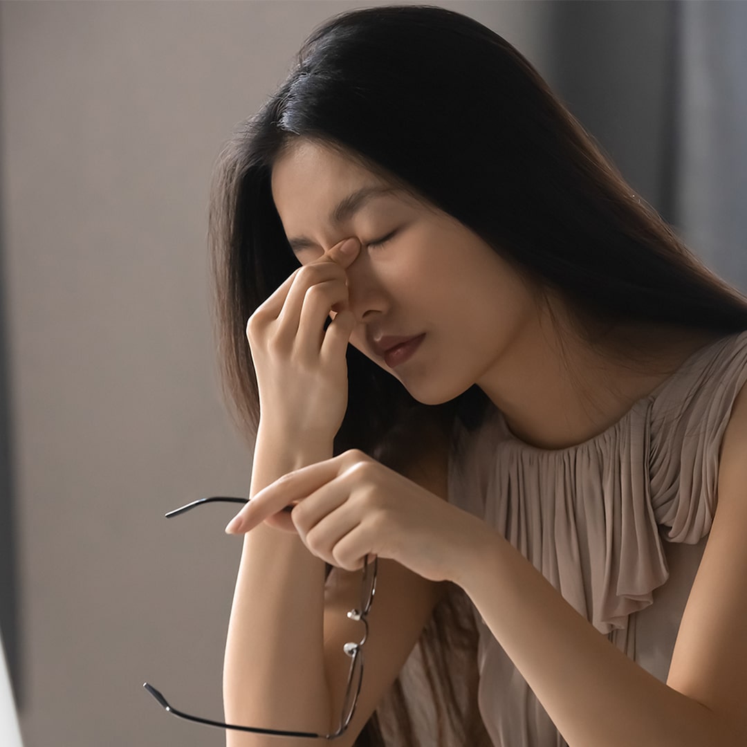 woman taking off her glasses due to sinus pain