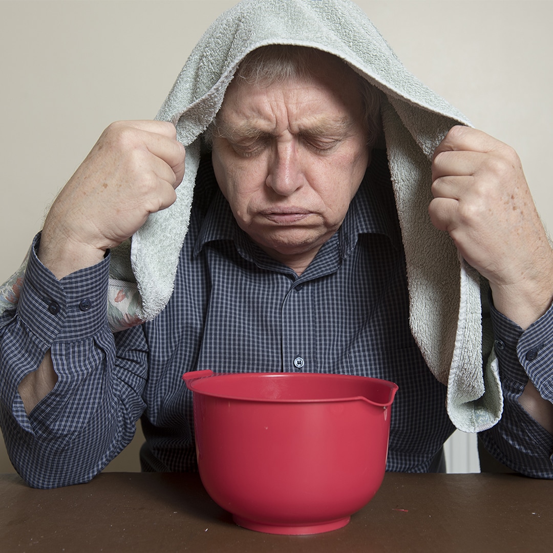 man breathing in steam from bowl of hot water