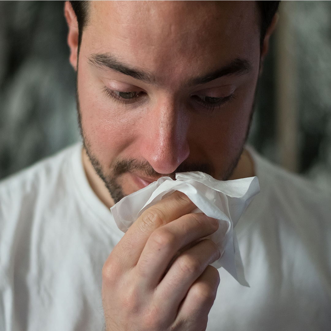 man wiping his nose after sneeze