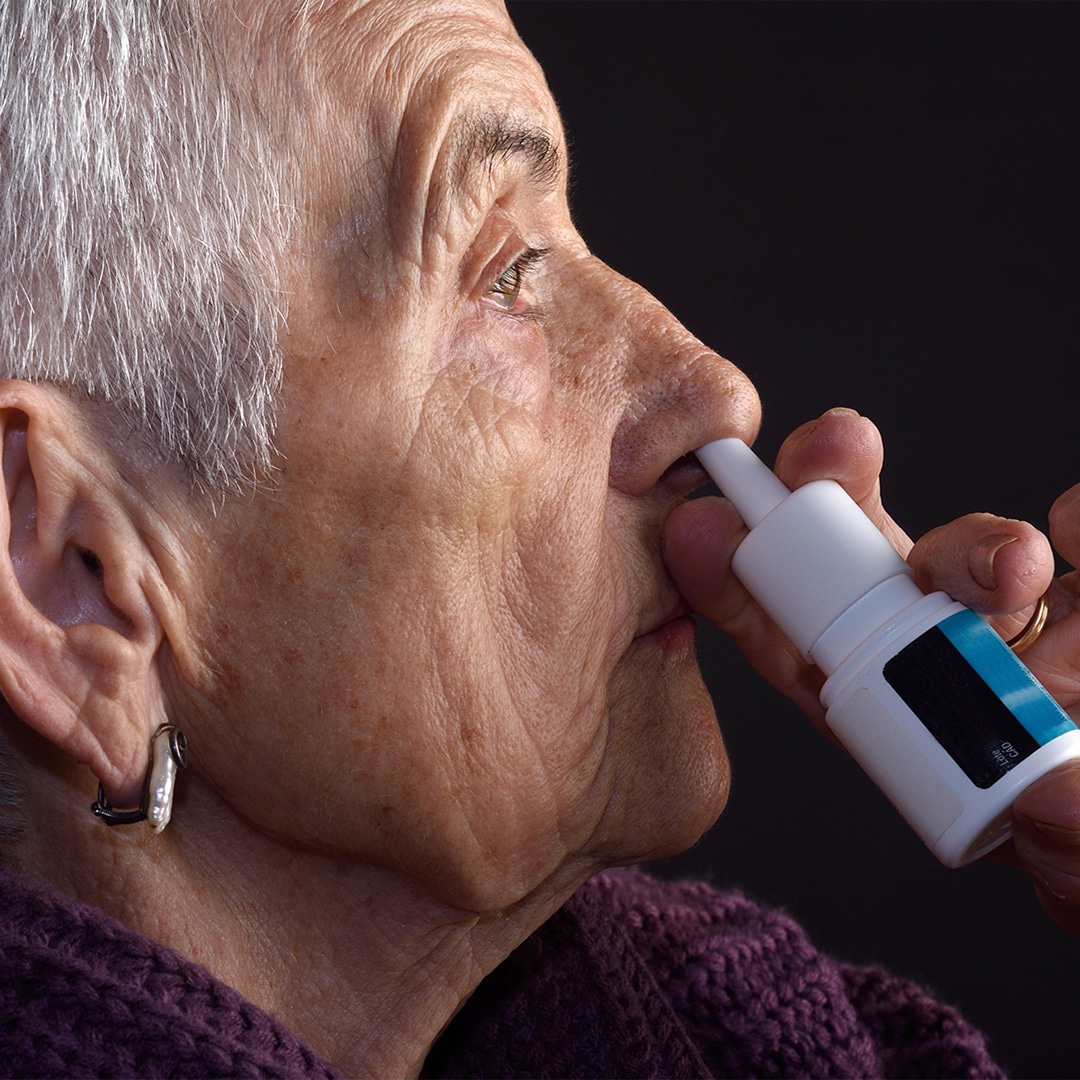 person spraying decongestant into nostril