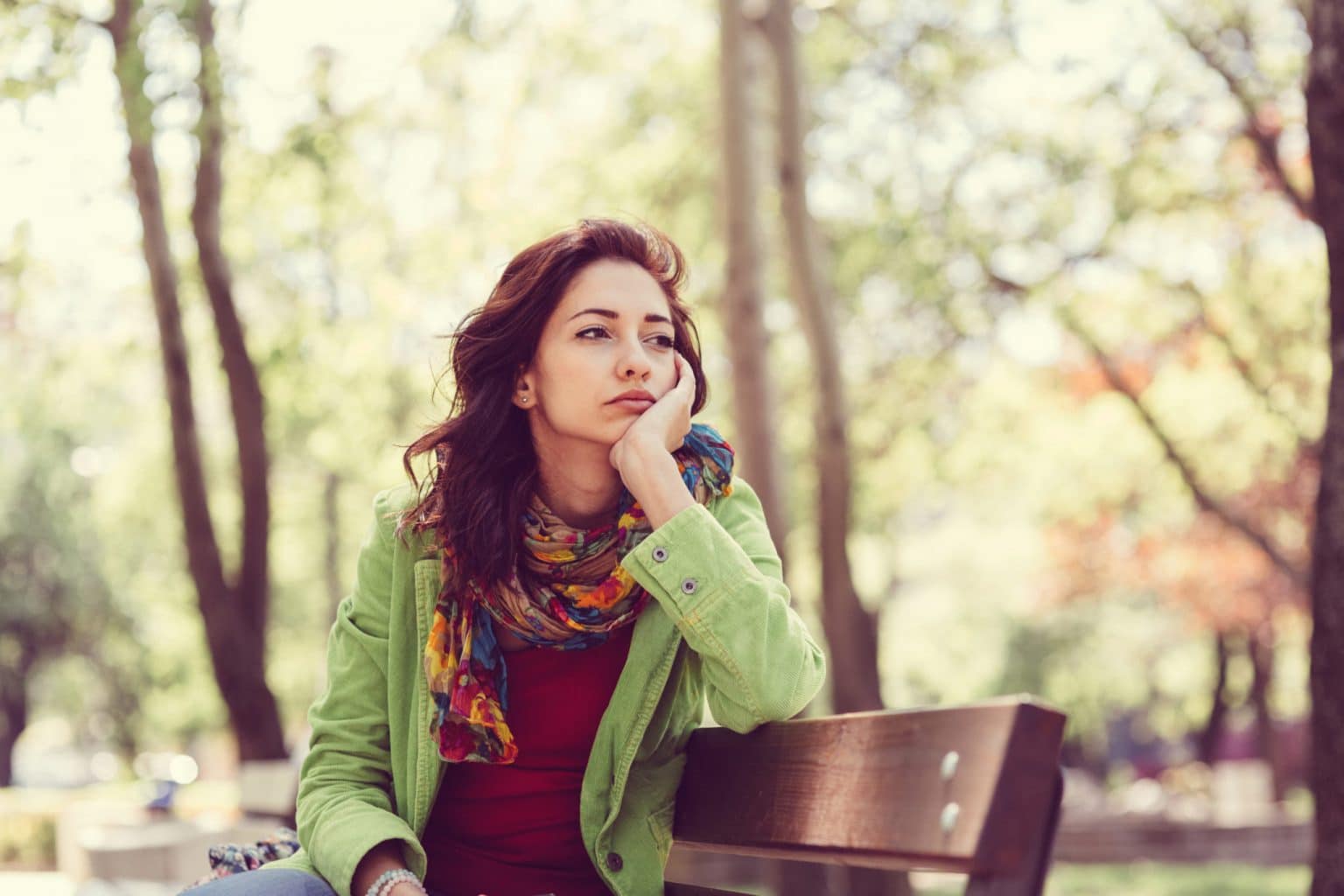 Nose-Loss-of-Smell Woman sitting on a park bench with an uninterested expression because she can't smell anything.