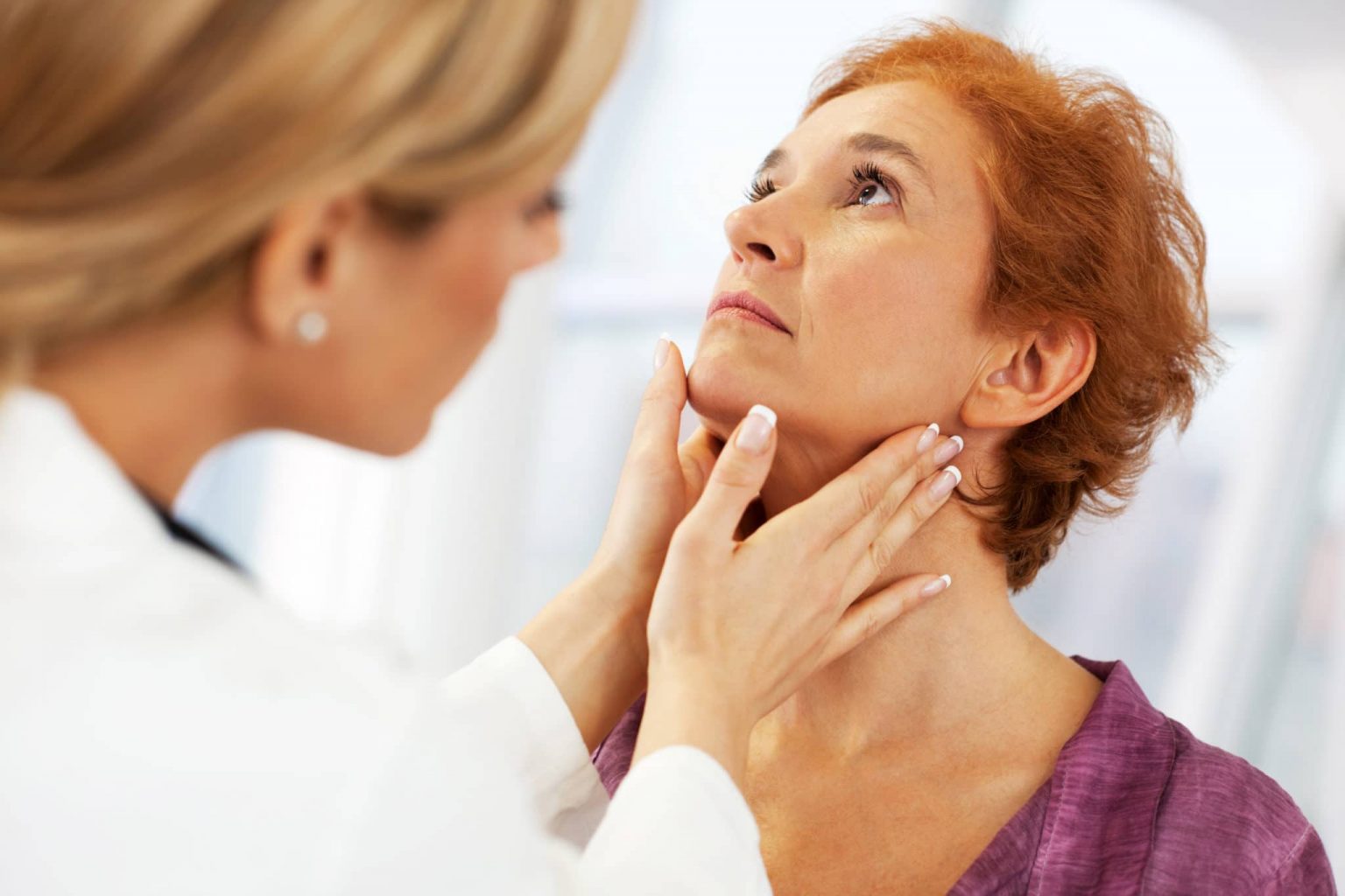 Otolaryngologist feeling a patient's neck checking for tonsillitis.