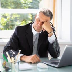 Tired man sitting at his desk using a laptop