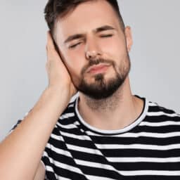 Man holds hand over ear