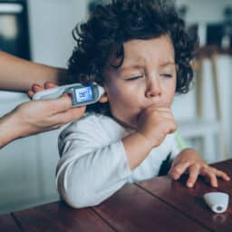 Sick coughing toddler having his temperature taken