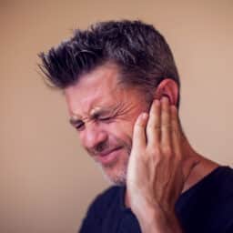 Man with ear pain holding his ear