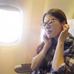 Woman holding her ears because of ear popping on a flight