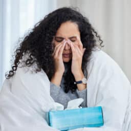 Woman wrapped in a blanket holding her sinuses