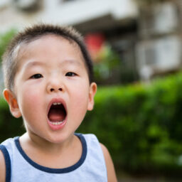 Young boy holding his mouth open.