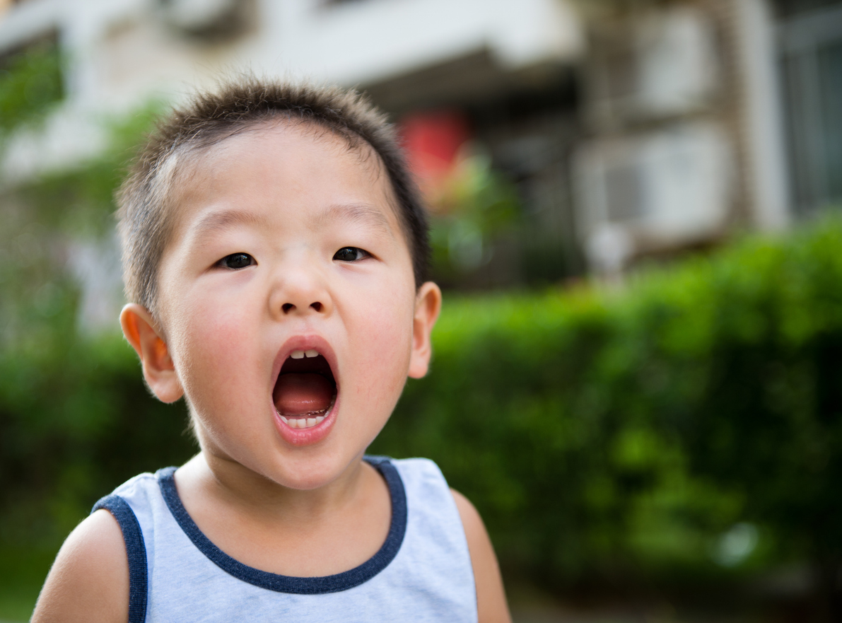 Young boy holding his mouth open.