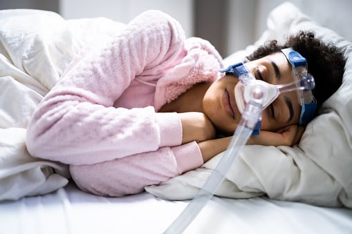 Woman sleeping with a CPAP mask.
