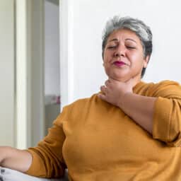 Woman holding her throat, looking uncomfortable.