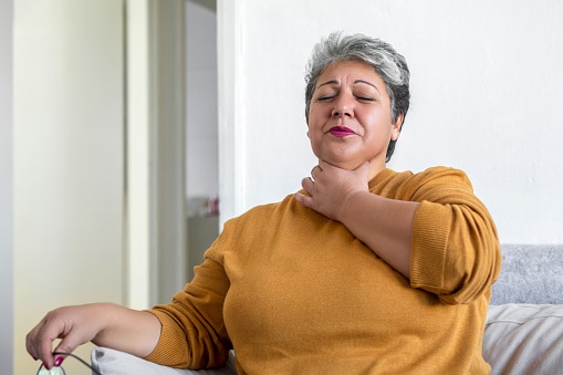 Woman holding her throat, looking uncomfortable.