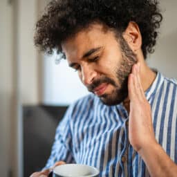 Man with tooth pain holding his jaw.
