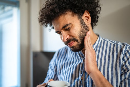 Man with tooth pain holding his jaw.