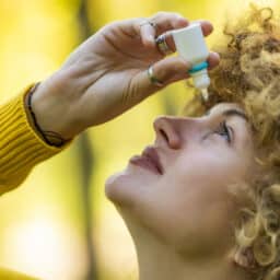Young woman putting eye drops in her eyes.