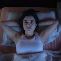 Woman lying awake in bed at night staring at ceiling