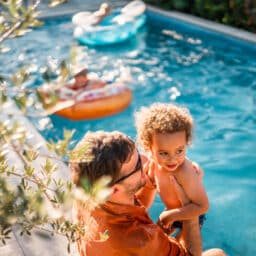 Dad and son sitting on the edge of the pool.