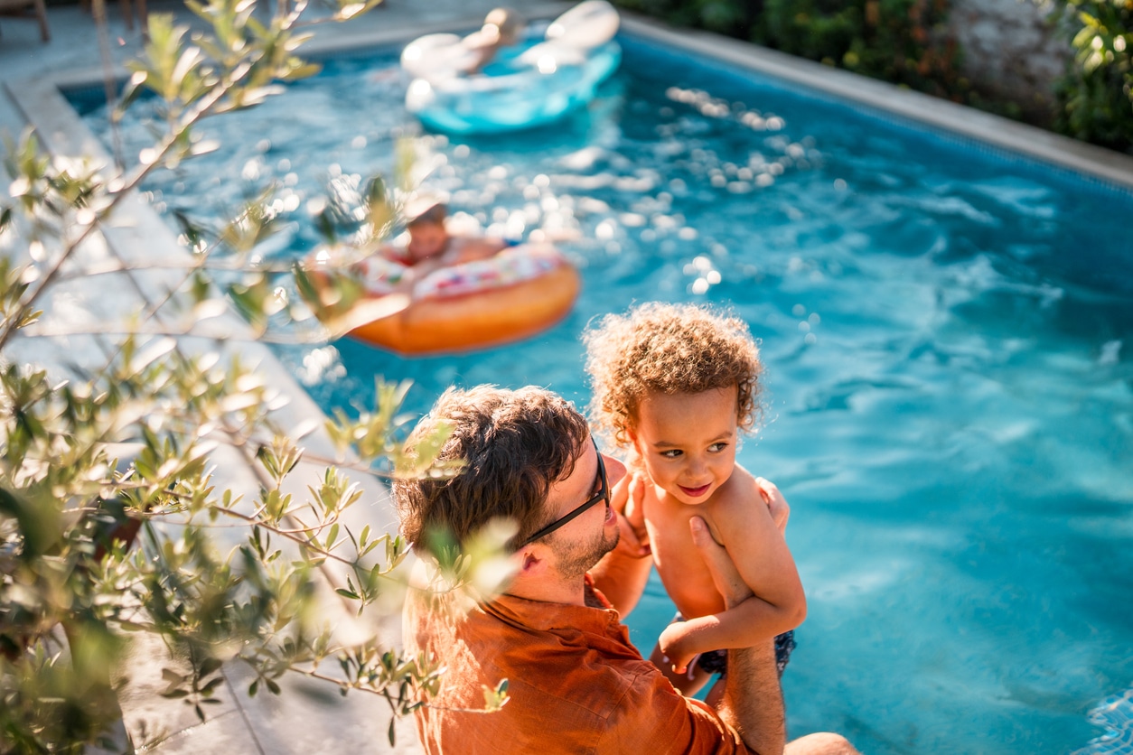 Dad and son sitting on the edge of the pool.