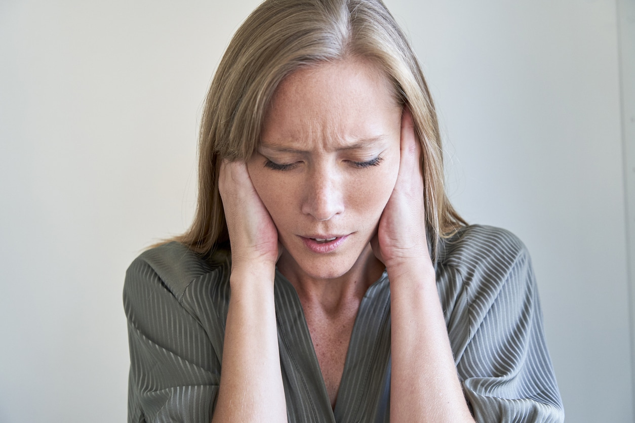 Close-up of young woman with eyes closed covering her ears