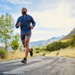Man running on a road near the mountains.