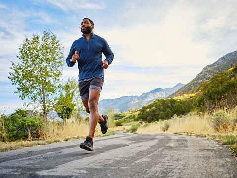 Man running on a road near the mountains.